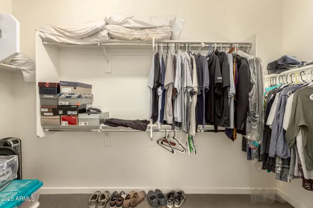 a view of walk in closet with clothes and shoes