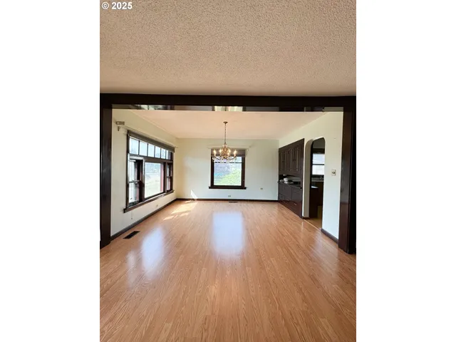 a view of a hallway with wooden floor and a living room