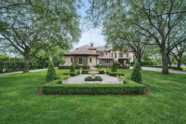 a front view of a house with garden and trees