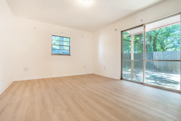 an empty room with wooden floor and windows
