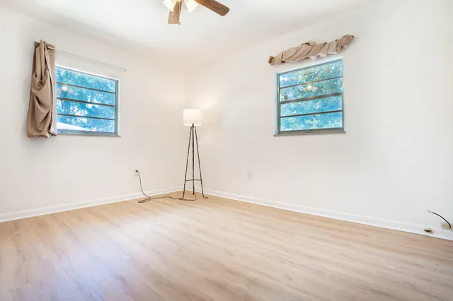 an empty room with wooden floor cabinet and windows