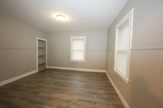 an empty room with wooden floor and windows