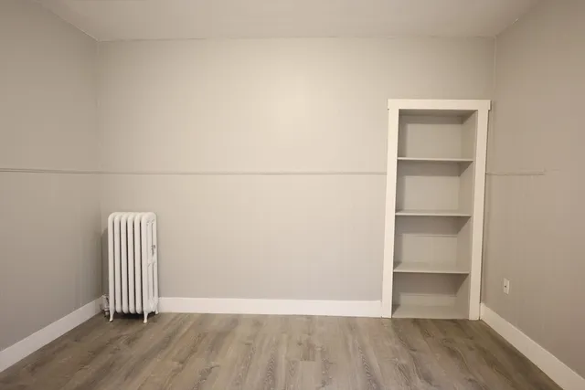 an empty room with wooden floor and a window
