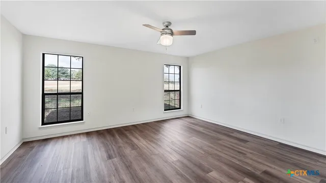a view of a white house next to a yard with large trees
