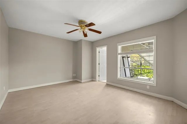 an empty room with windows and fan