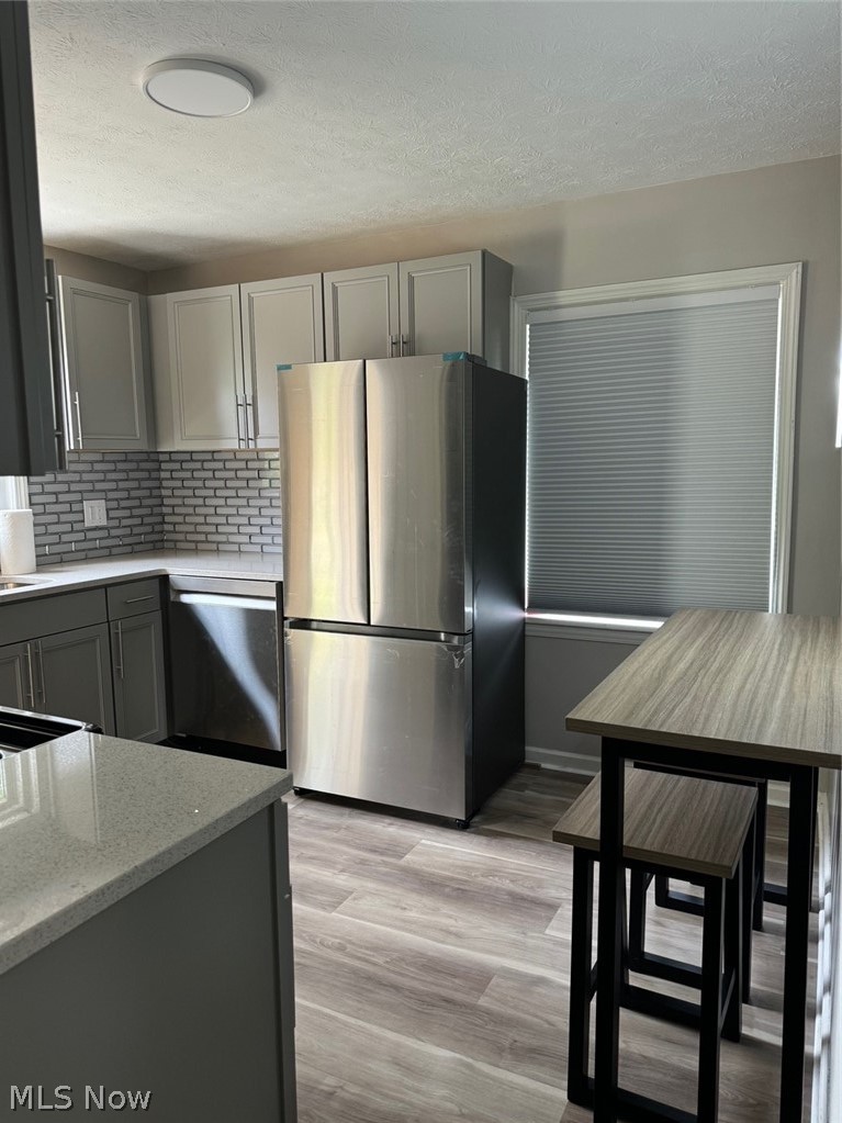 5671 Wellington Road Cleveland, OH 44124 - Photo 10 of 26 Kitchen with gray cabinets, stainless steel refrigerator, dishwasher, and light wood-type flooring