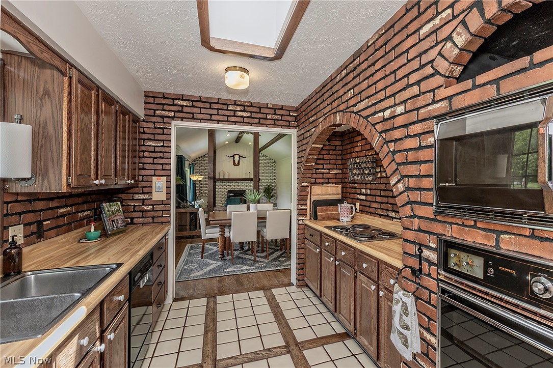 11292 Butternut Road Chardon, OH 44024 - Photo 19 of 49 Brick-clad kitchen featuring an arched alcove, wood-finish countertops, and integrated appliances