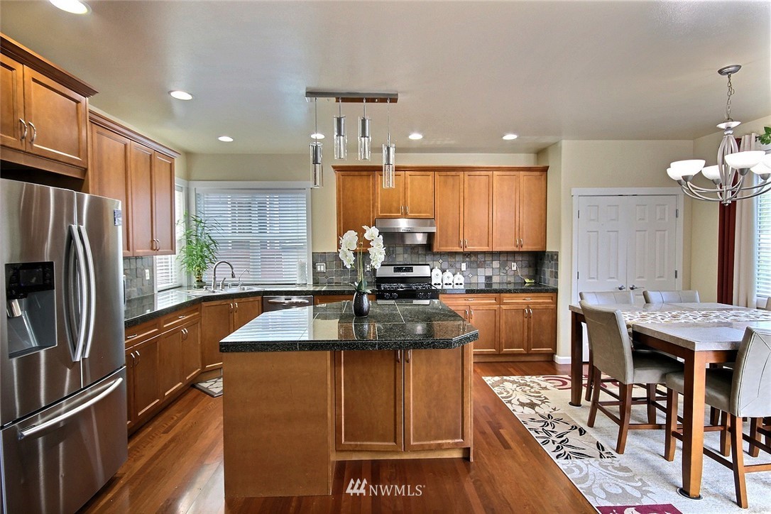 12946 Southeast 216th Place Kent, WA 98031 - Photo 11 of 39 a kitchen with stainless steel appliances granite countertop sink stove refrigerator dining table and chairs