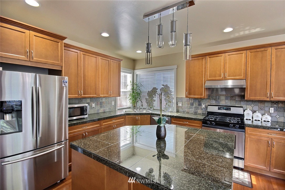 12946 Southeast 216th Place Kent, WA 98031 - Photo 7 of 39 a kitchen with stainless steel appliances granite countertop a sink a stove and a refrigerator