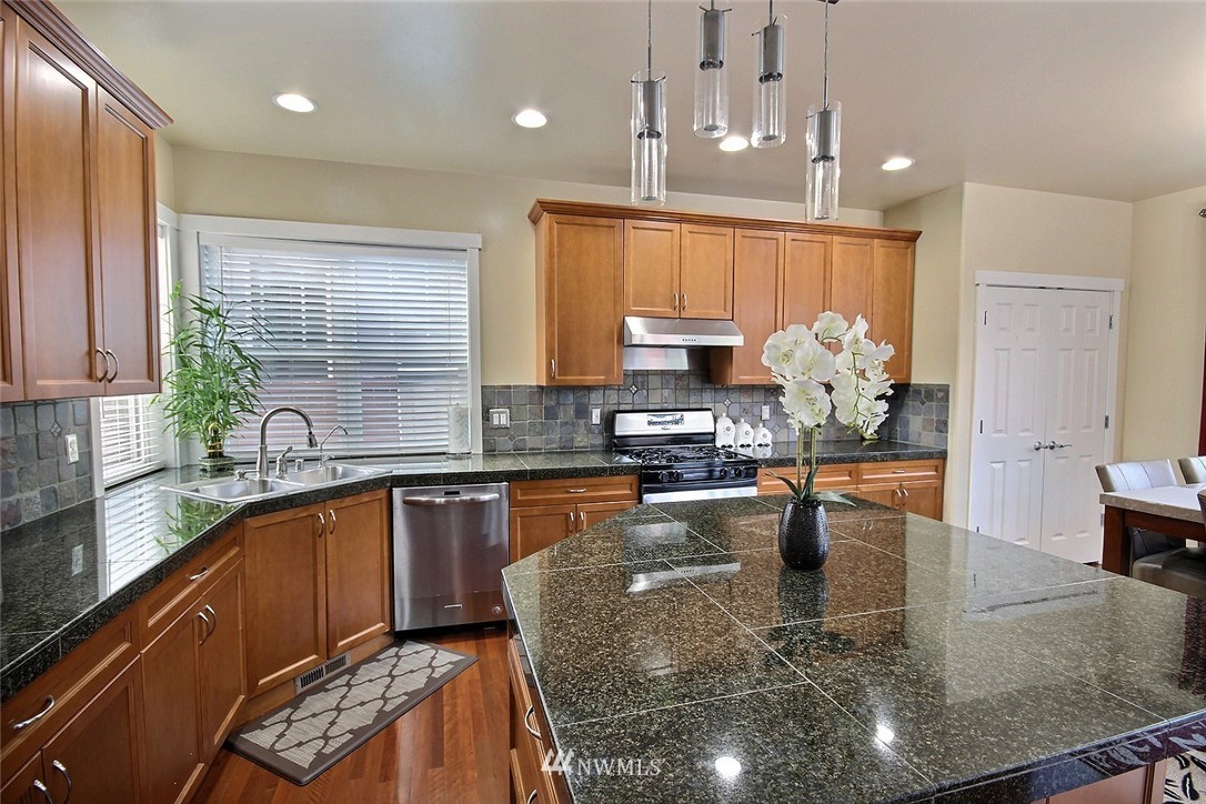 12946 Southeast 216th Place Kent, WA 98031 - Photo 10 of 39 a kitchen with kitchen island granite countertop a sink cabinets and window