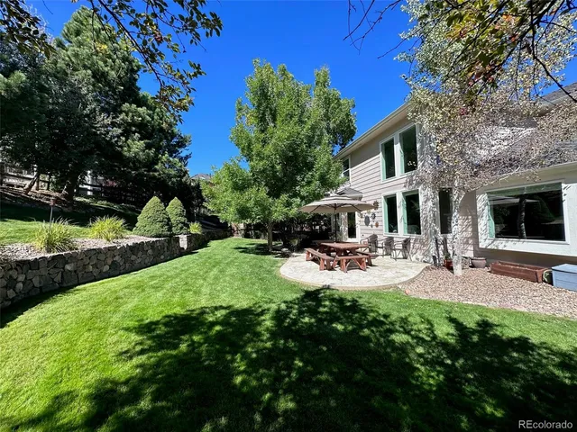 a view of backyard of a house with table and chairs and potted plants
