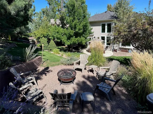 a view of a patio with table and chairs potted plants and large tree