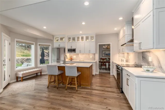 a large kitchen with kitchen island a dining table chairs and white cabinets