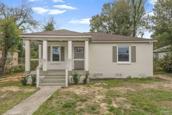 a view of a house with a small yard and a large tree