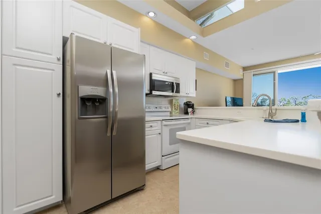 a kitchen with cabinets appliances a sink and a window