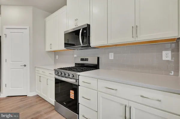 a kitchen with stainless steel appliances granite countertop white cabinets and a stove a oven with white countertops