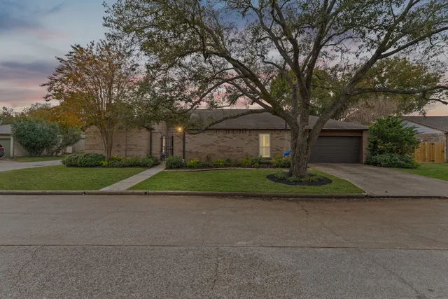 a view of a house with a big yard and large trees