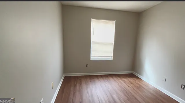 an empty room with wooden floor and window