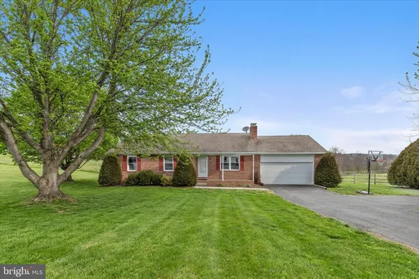 a view of house with a big yard and large trees