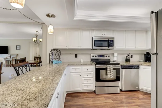 a kitchen with stainless steel appliances granite countertop a stove top oven a sink a dining table and chairs with wooden floor