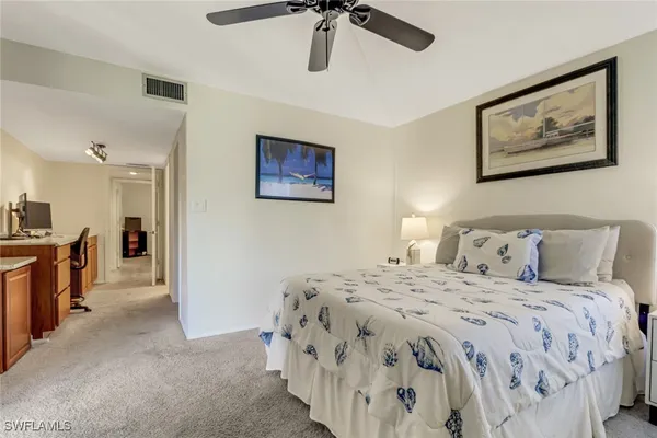 a spacious bedroom with a bed and a view of kitchen
