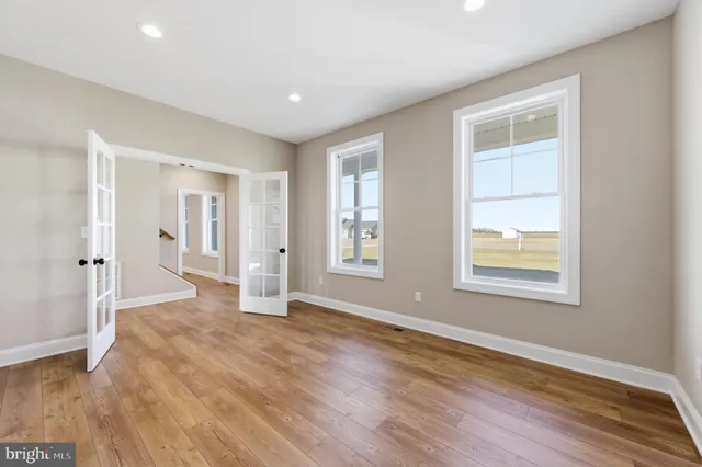 an empty room with wooden floor and windows