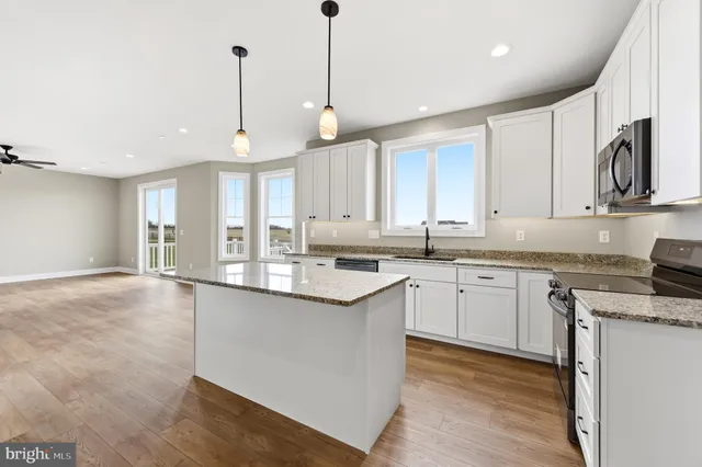 a kitchen with stainless steel appliances granite countertop a sink a stove and a wooden floors