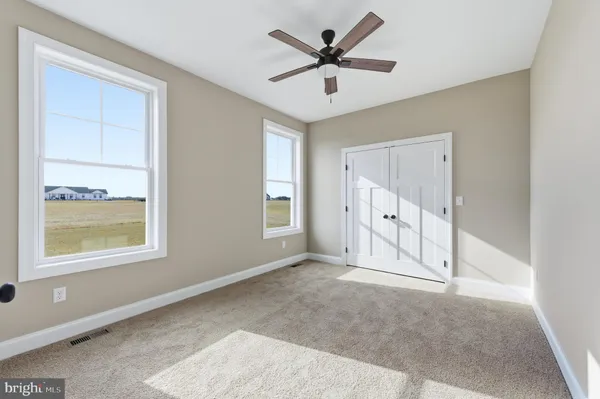 an empty room with windows and ceiling fan