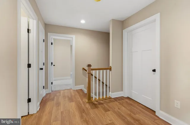 a view of a hallway with wooden floor and a bathroom