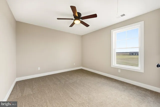 an empty room with a ceiling fan and window
