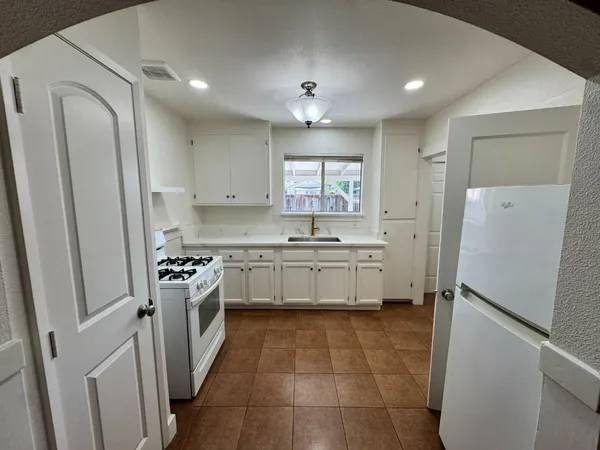 a kitchen with a sink a refrigerator a stove top oven and cabinets
