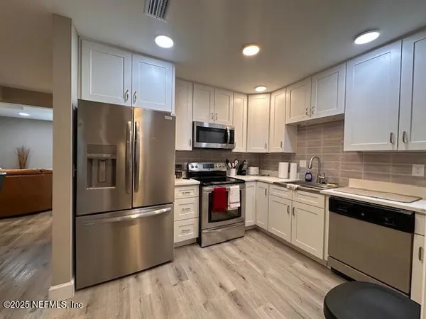a kitchen with cabinets stainless steel appliances and a window