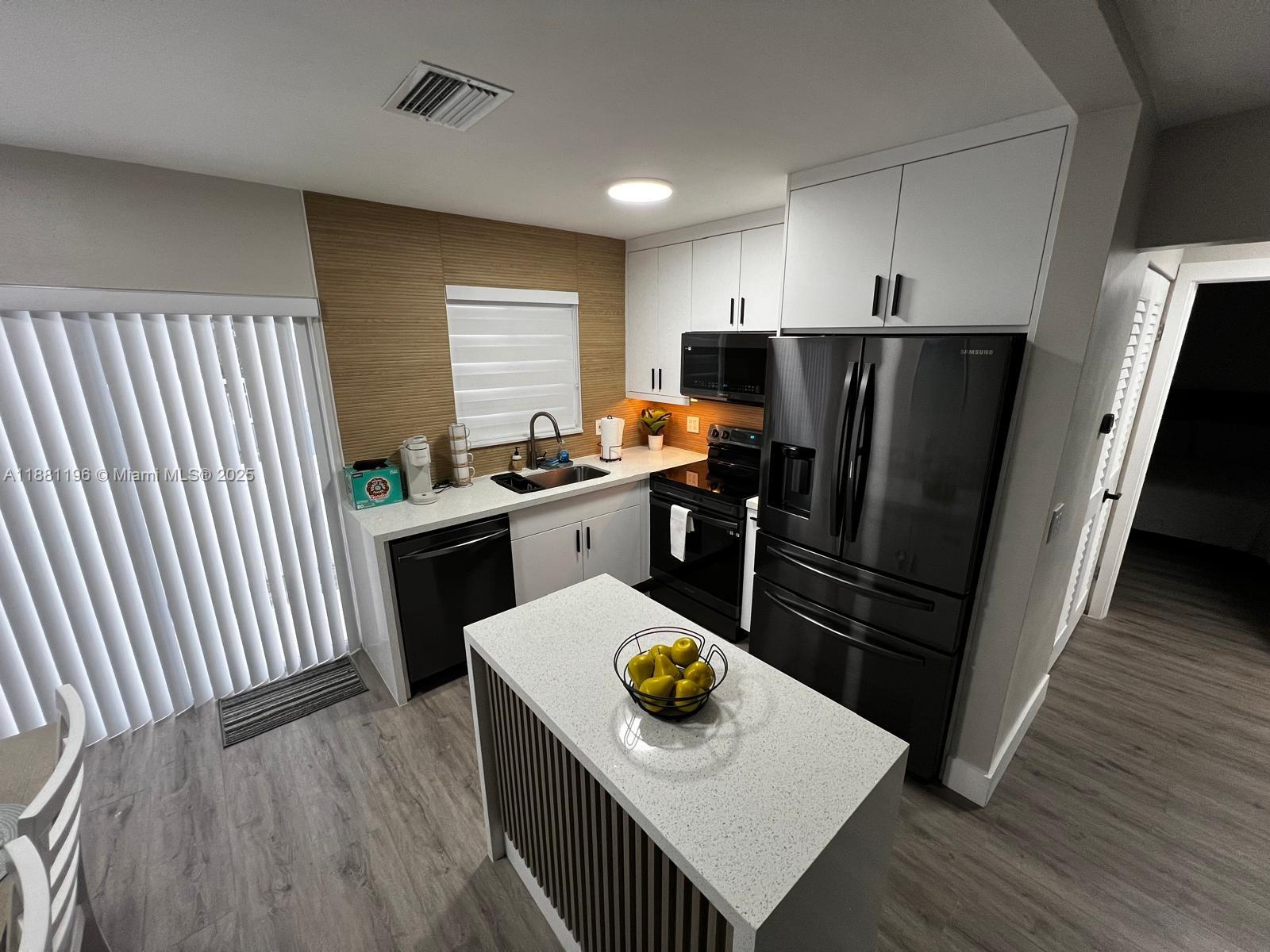 222 Southwest 8th Street, Unit A Dania Beach, FL 33004 - Photo 4 of 16 a kitchen with stainless steel appliances wooden floor sink stove refrigerator and wooden floor