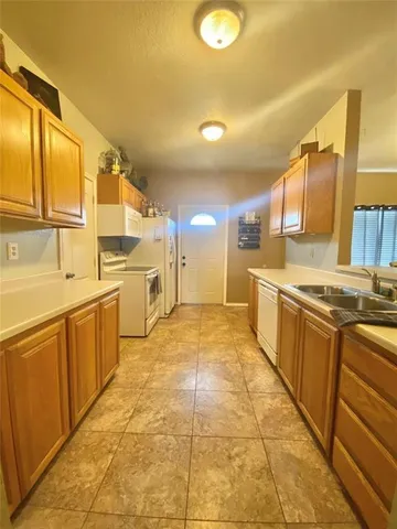 a large kitchen with a stove a sink dishwasher a refrigerator with wooden cabinets and floor
