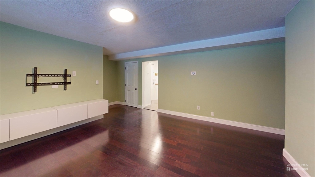 31 Westgate Road, Unit 1 Boston, MA 02467 - Photo 3 of 10 an empty room with wooden floor and windows