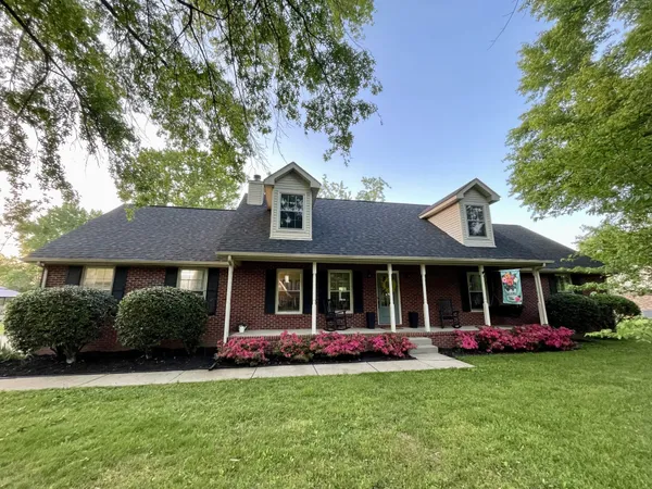 a front view of a house with a garden and trees