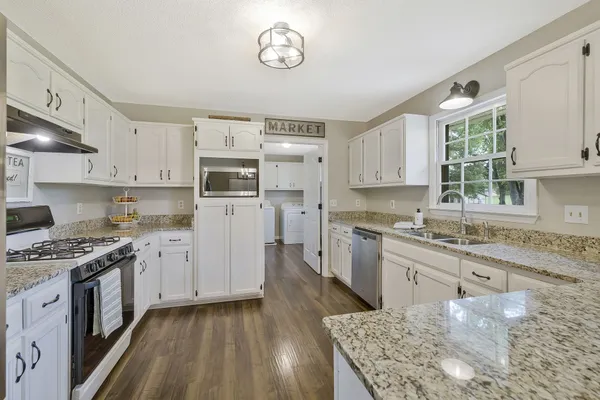 a kitchen with stainless steel appliances granite countertop a stove top oven a sink dishwasher and a refrigerator with wooden cabinets