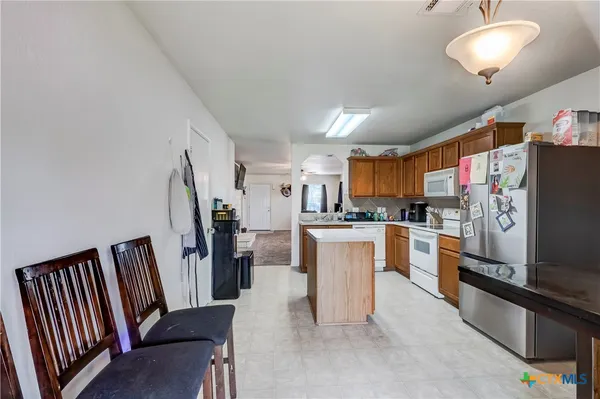 a kitchen with stainless steel appliances kitchen island granite countertop a refrigerator and a stove top oven
