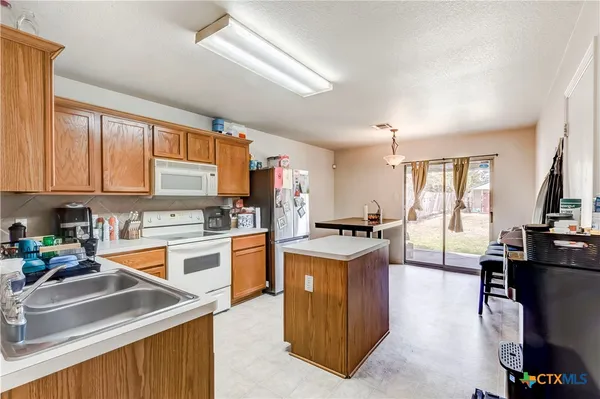 a kitchen with stainless steel appliances granite countertop a refrigerator a stove a sink dishwasher and white cabinets with wooden floor