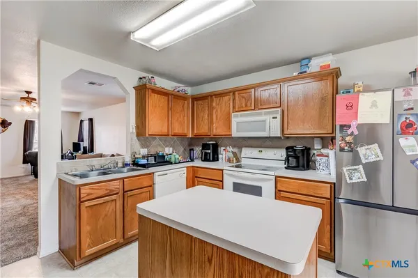 a kitchen with stainless steel appliances granite countertop a refrigerator sink stove microwave and cabinets