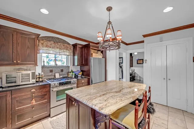 a kitchen that has a kitchen island a stove a table and chairs in it