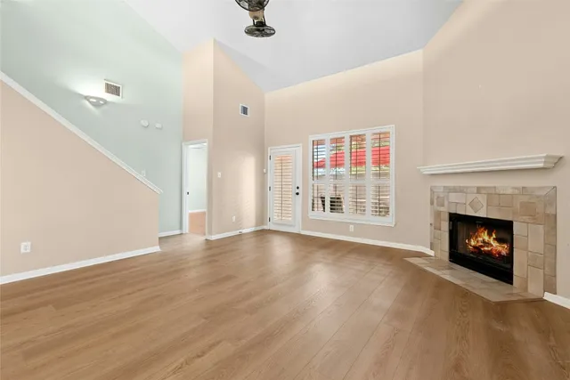 a view of an empty room with wooden floor fireplace and a window