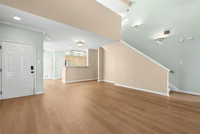 a view of an empty room with wooden floor and fireplace