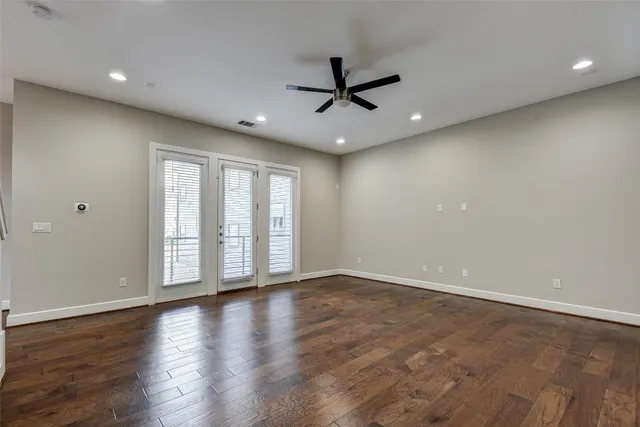 an empty room with a ceiling fan and wooden floor