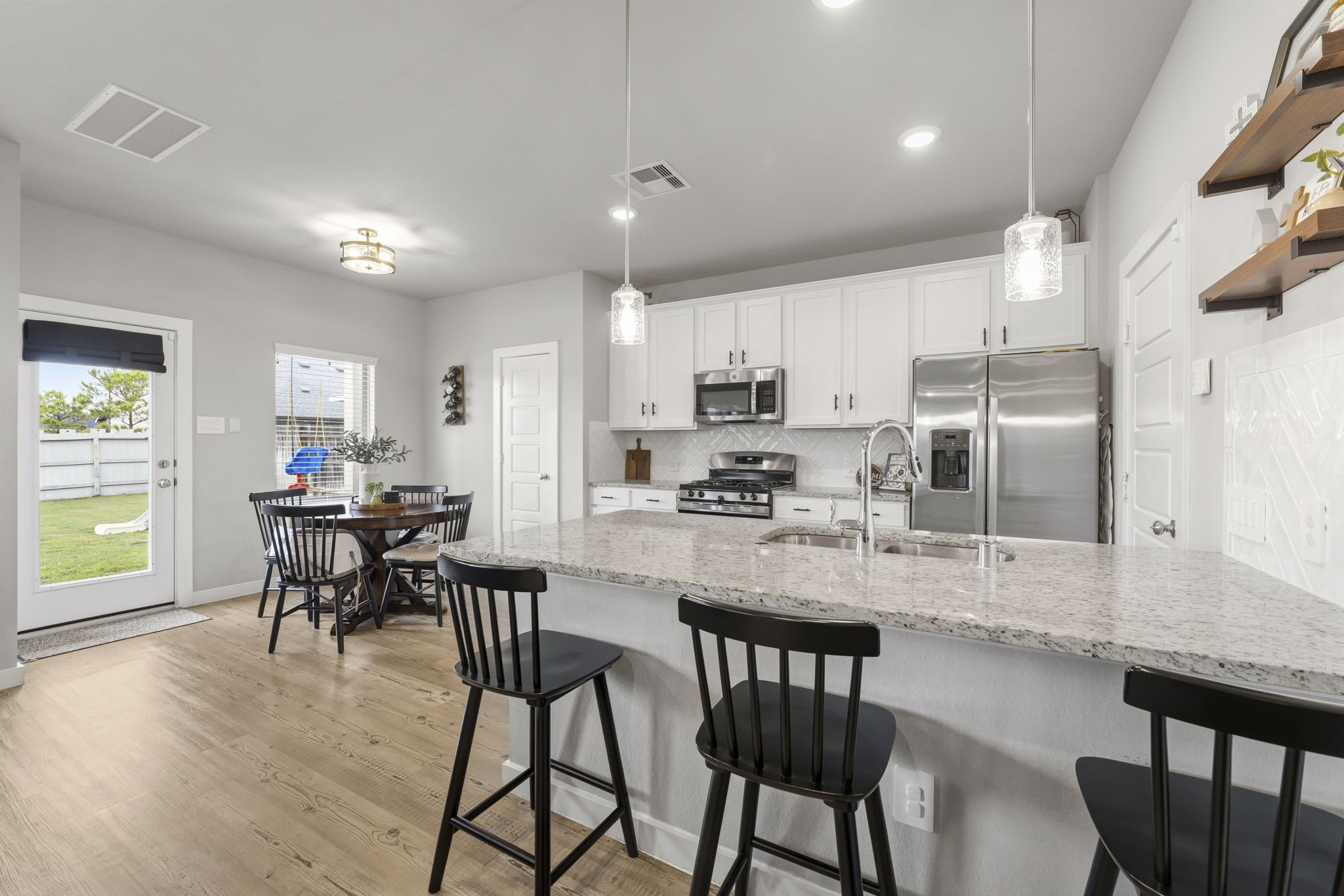 17696 Tree Of Heaven Conroe, TX 77385 - Photo 9 of 32 Appealing kitchen with white cabinets, durable granite counters and timeless herringbone backsplash.