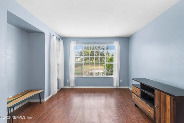 an empty room with wooden floor and windows
