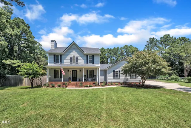 a view of house with a big yard and large trees
