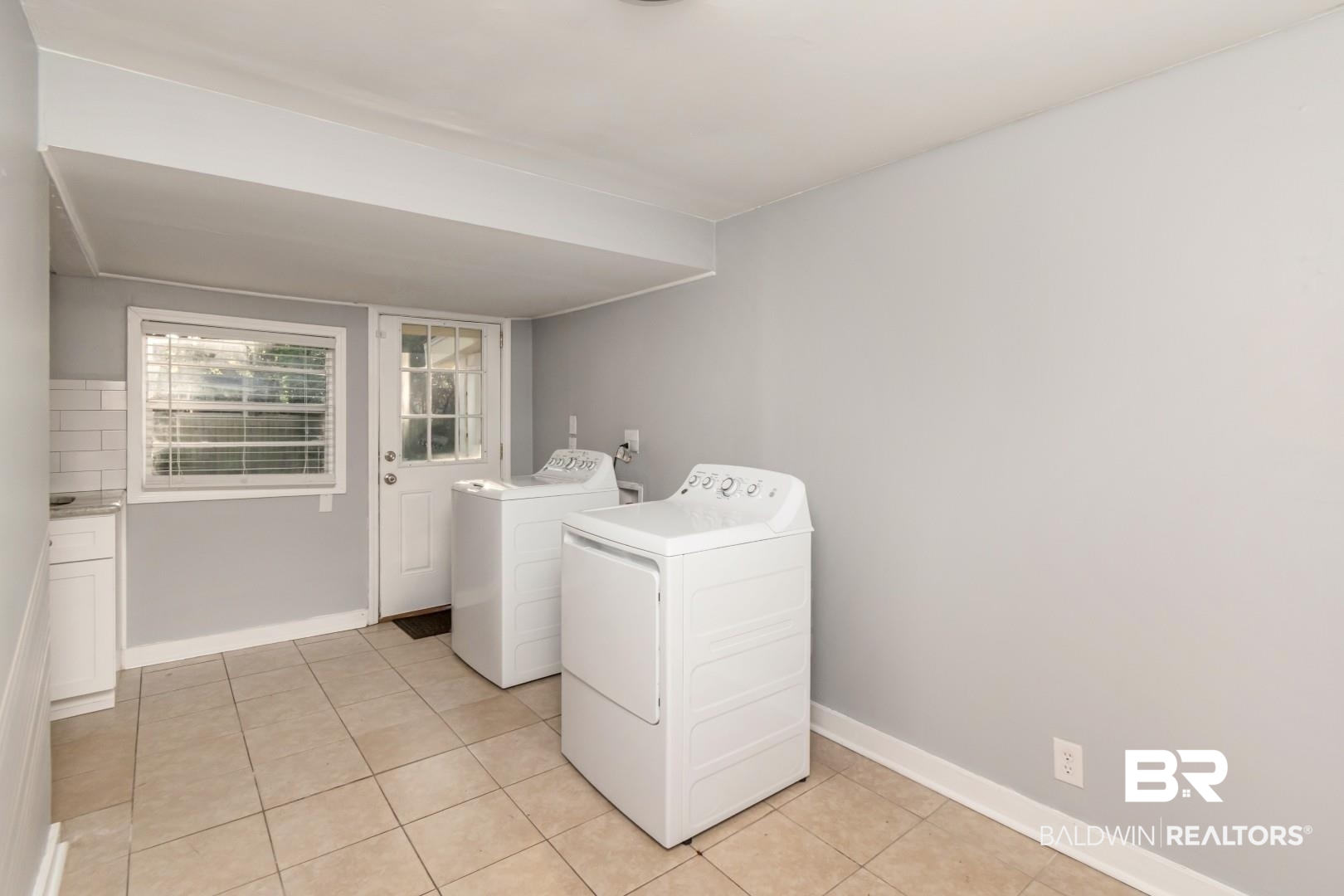 263 Border Drive East Mobile, AL 36608 - Photo 6 of 27 Utility area featuring neutral tile flooring, light gray walls, a window with blinds, and a white paneled door