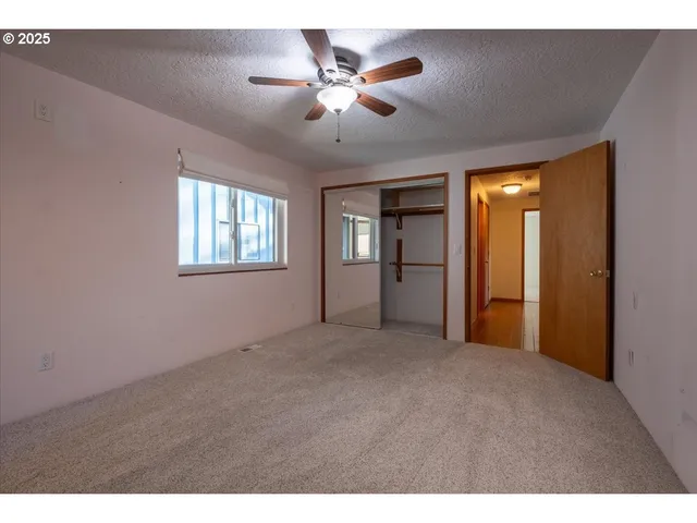 a view of an empty room with chandelier fan and windows