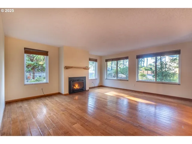 an empty room with wooden floor fireplace and windows